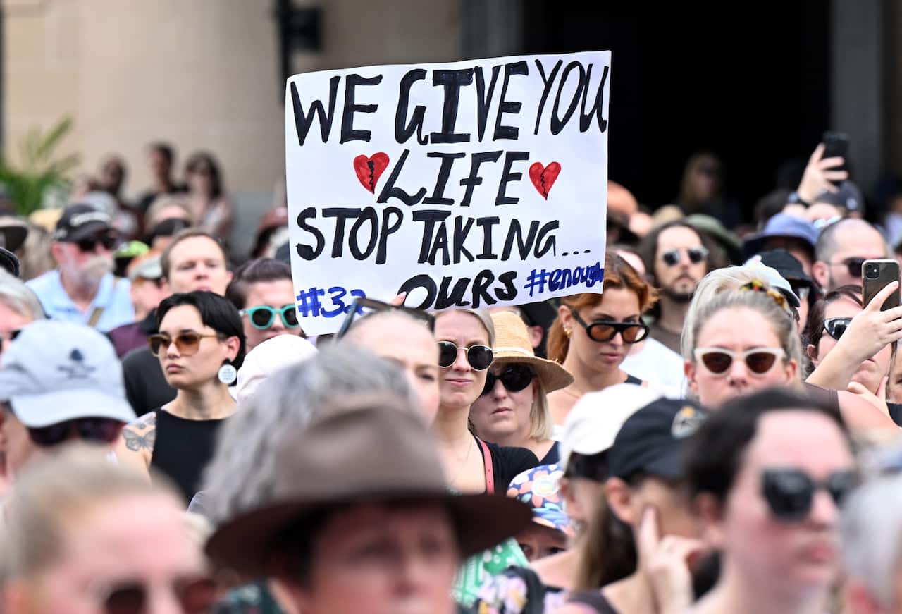 A woman holds up a banner in a crowd