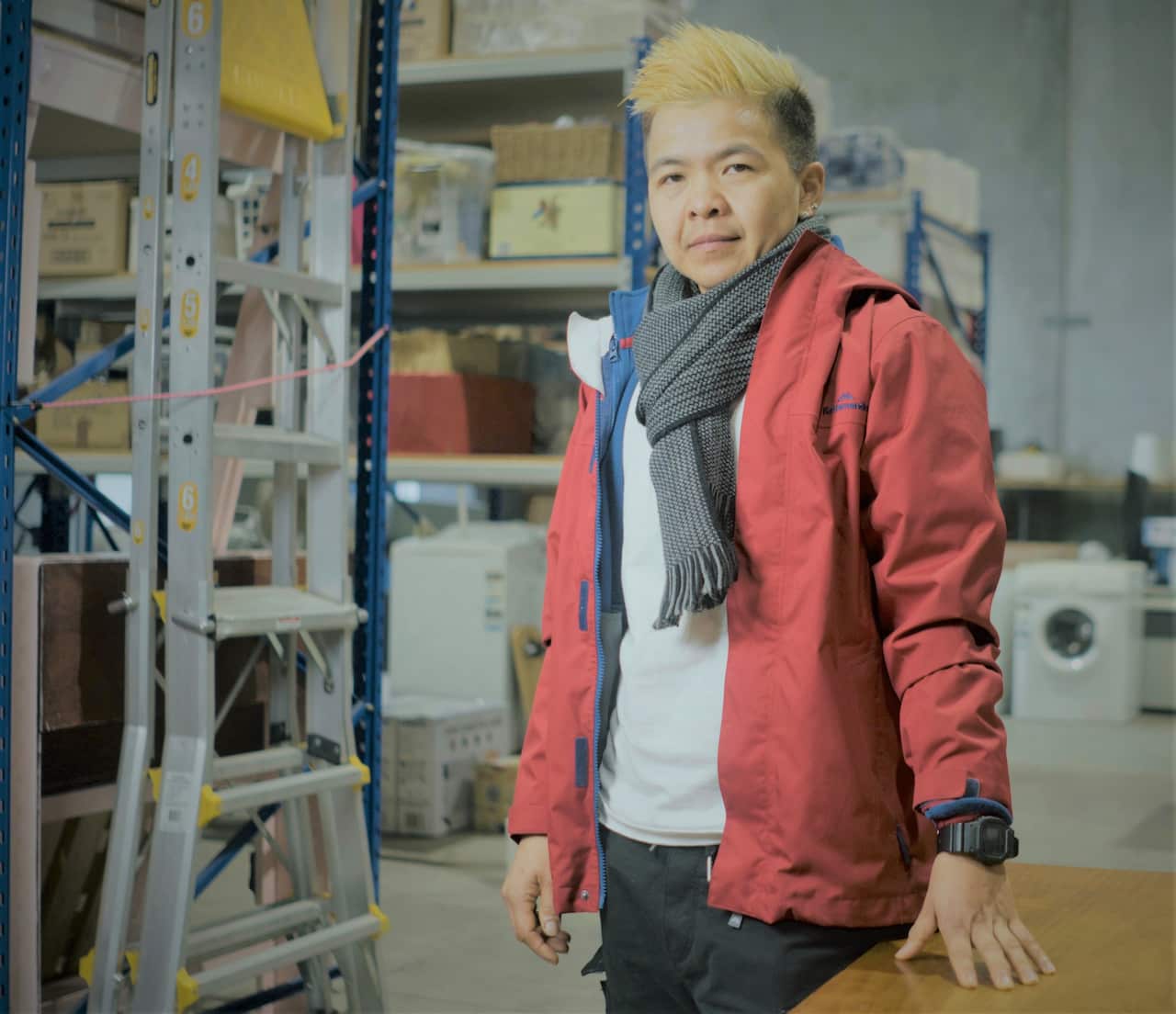 Tiff in a red coat standing inside a warehouse. 