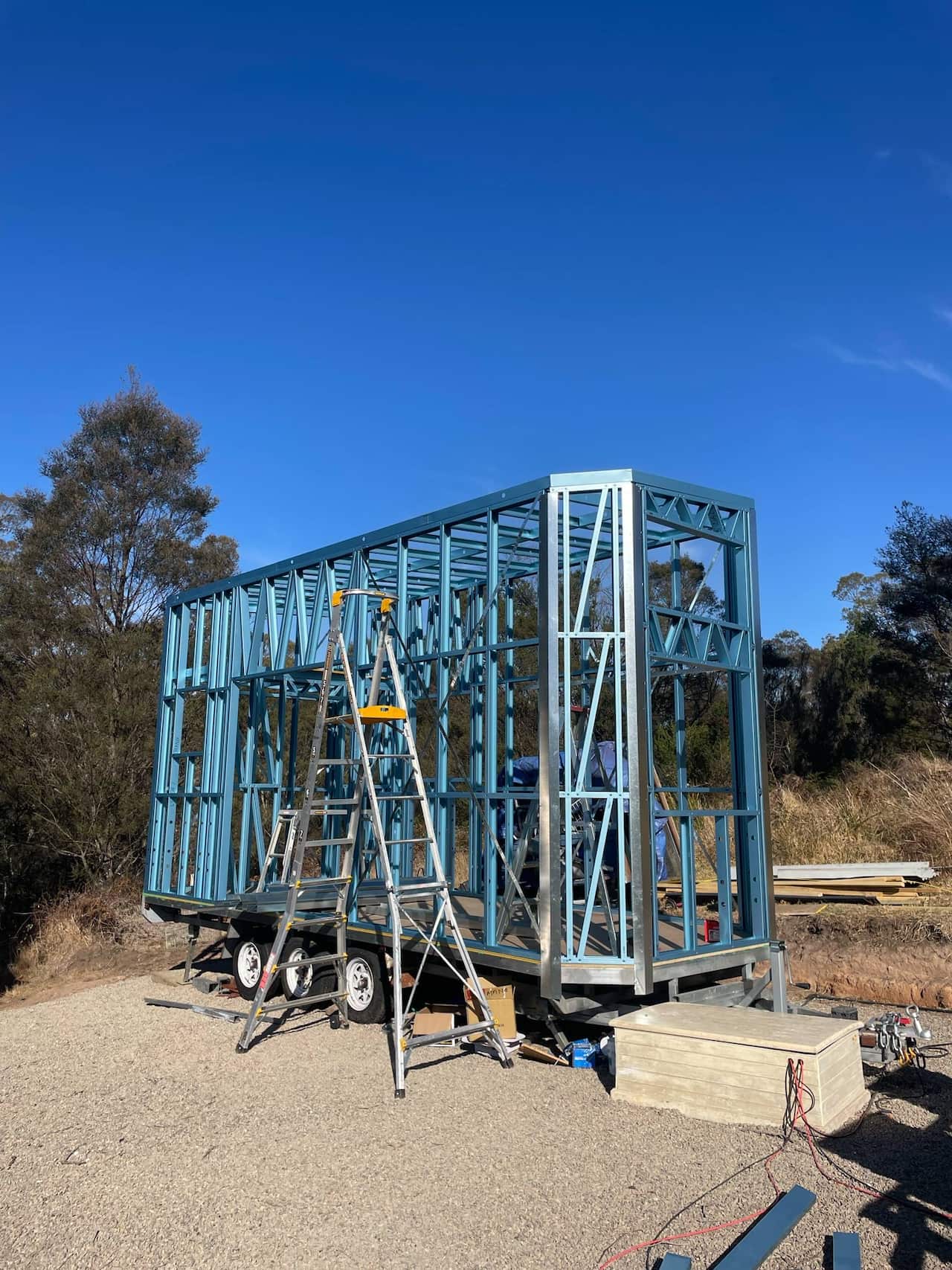 A scaffolded structure is atop a trailer with a ladder next to it 