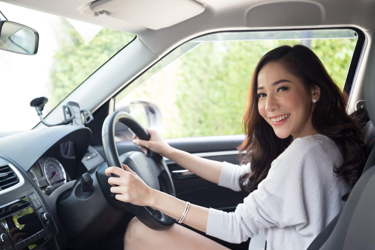 Side View Portrait Of Cheerful Young Woman Sitting In Car