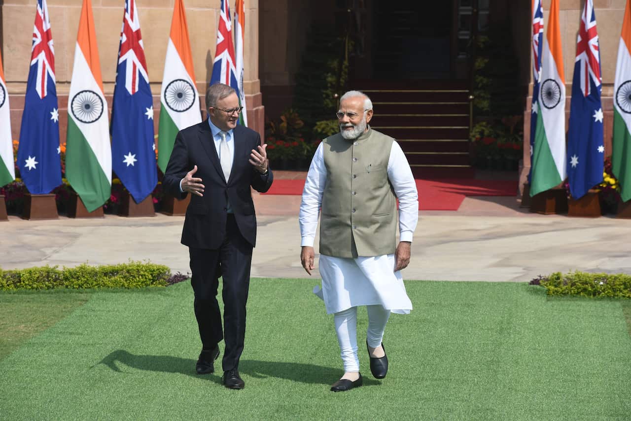 Two men walk on a lawn.