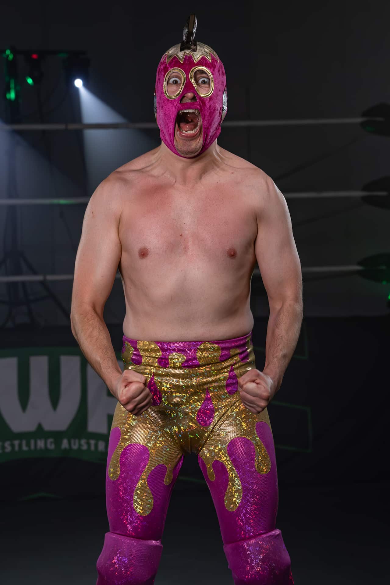 A man dressed up as a pro-wrestler with pink and gold pants and a pink mask.