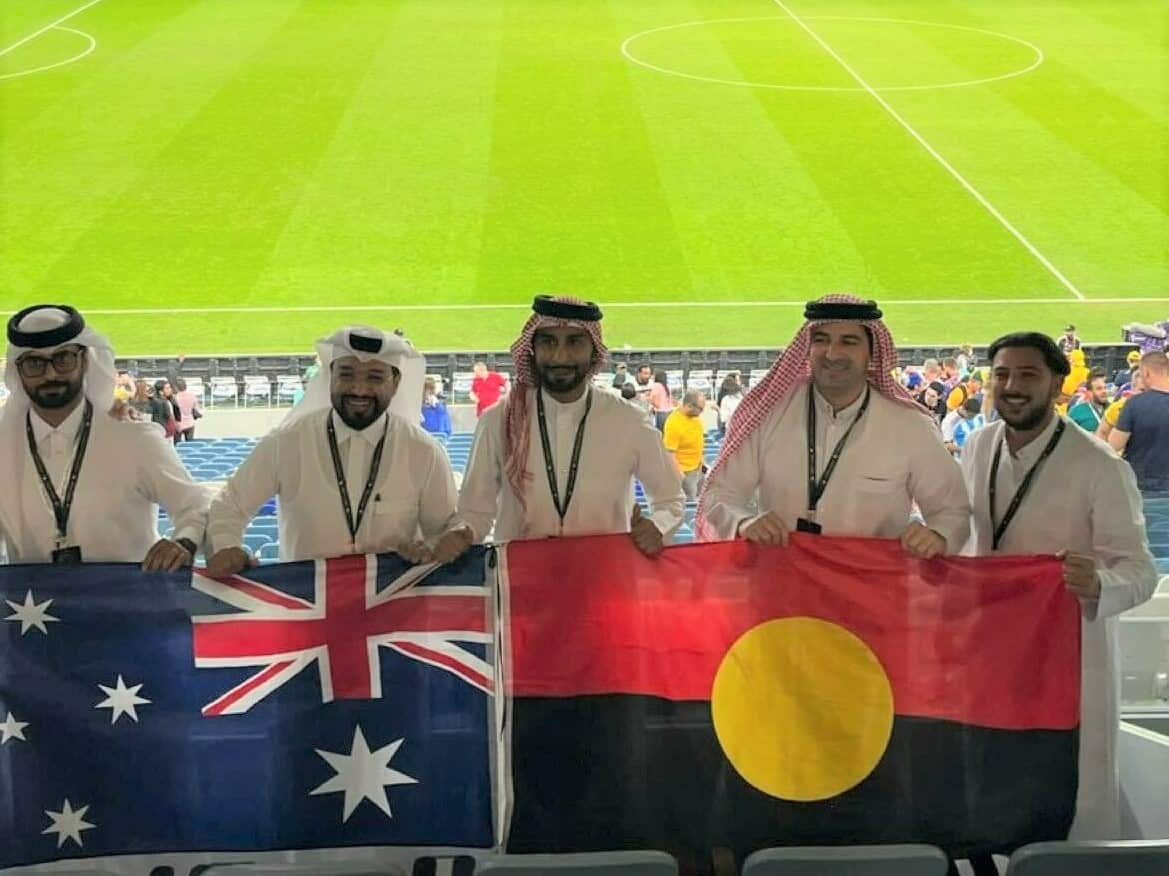 Men in thobes carry the Australian and Aboriginal flag.