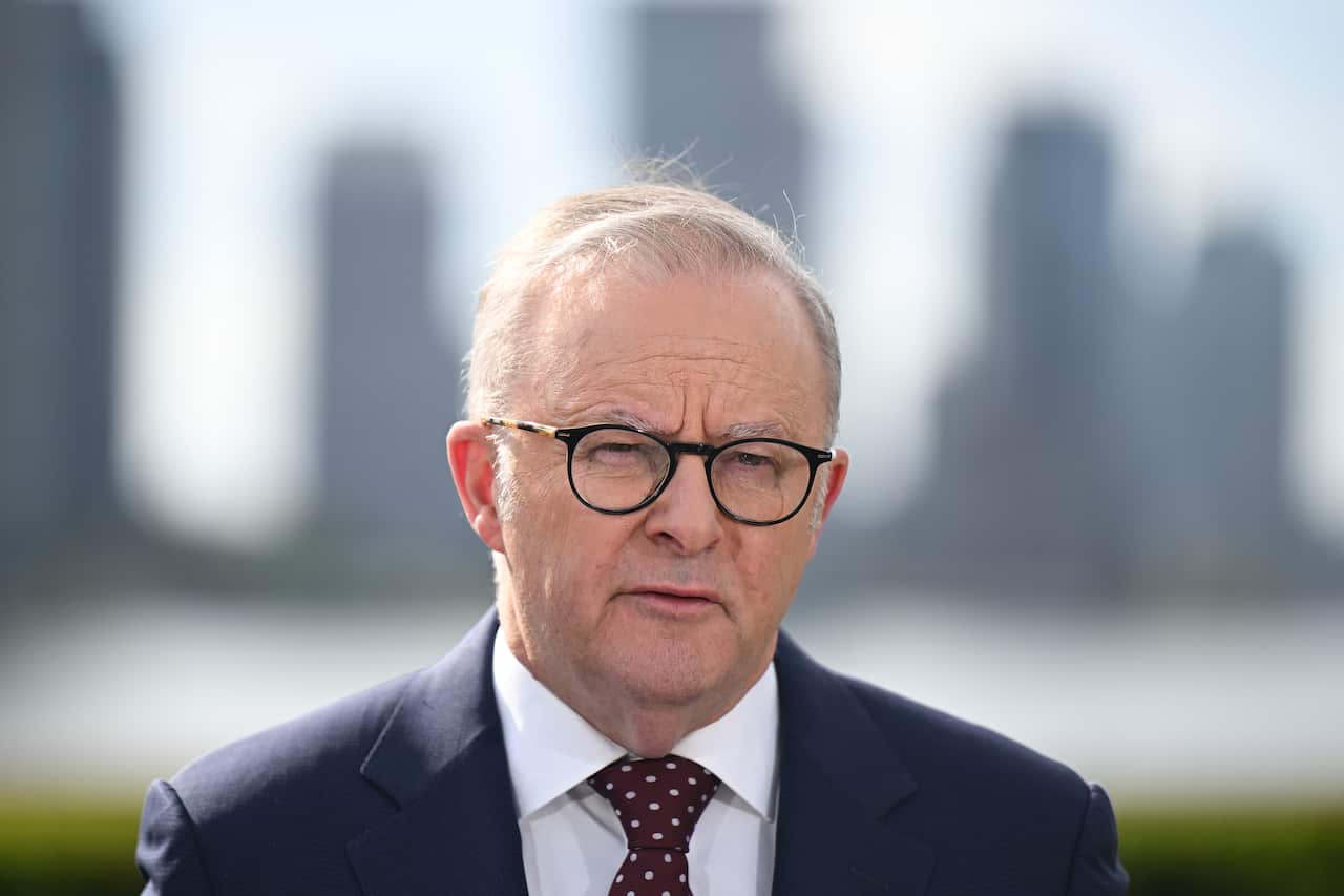 Anthony Albanese stands outside with a city skyline in the background.