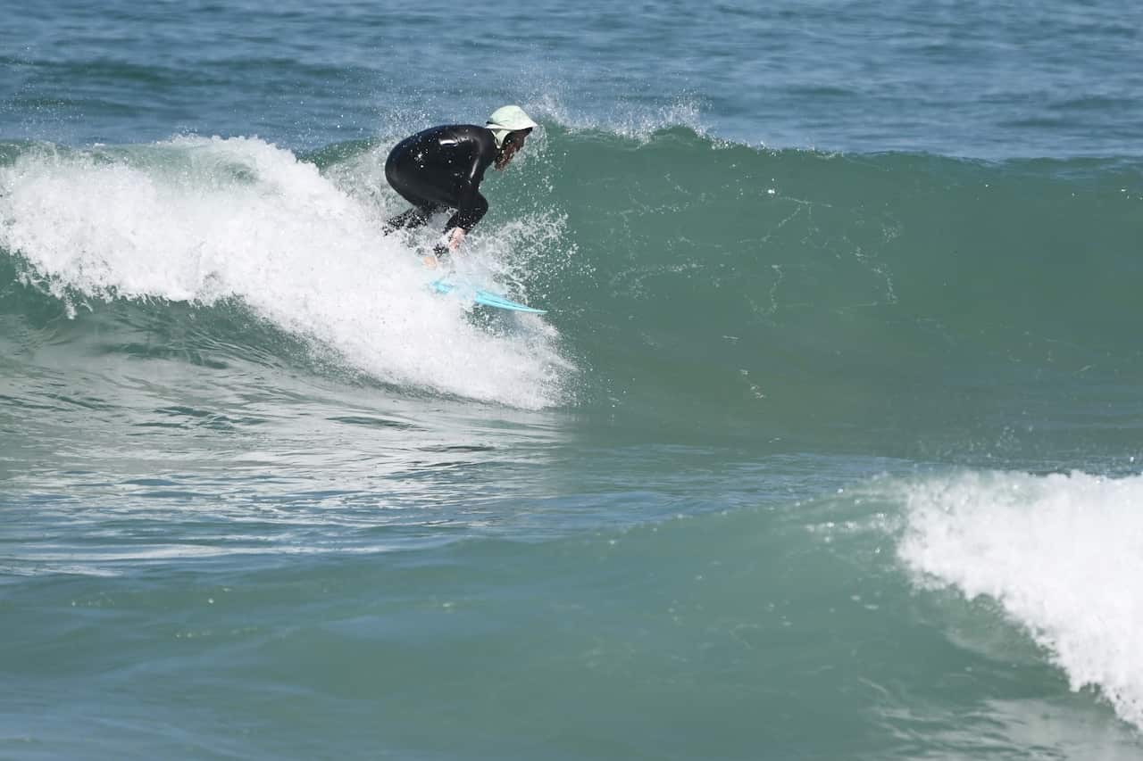 Blake Johnston crouches on a surfboard as rides a wave.