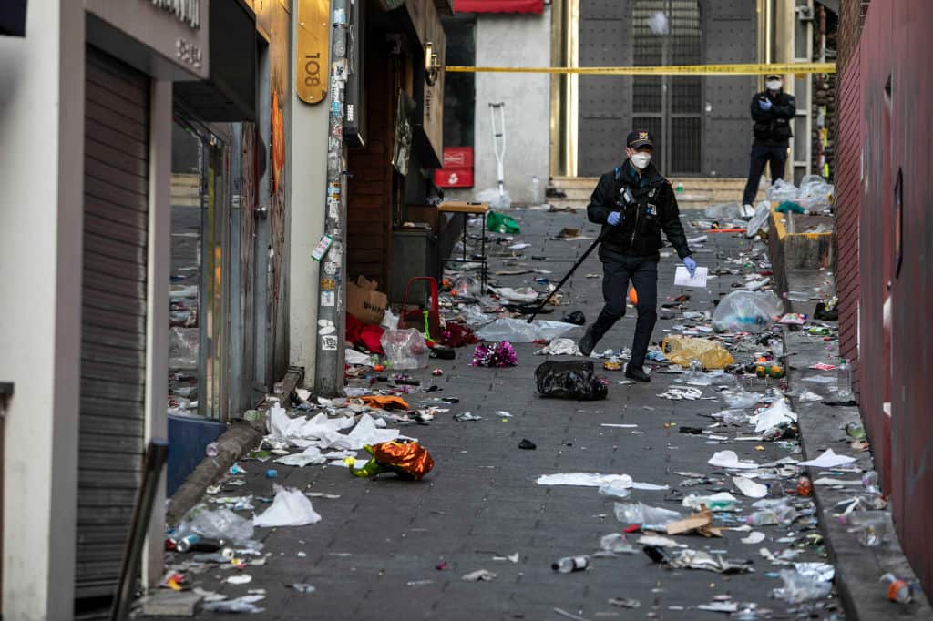 A policeman walks in an alley strewn with rubbish