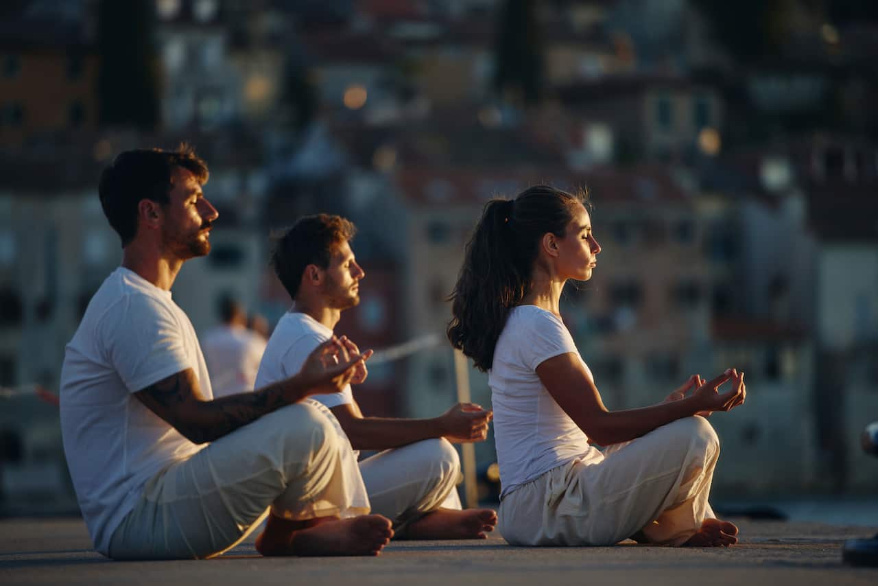 Athletic people meditating on a pier in summer day.