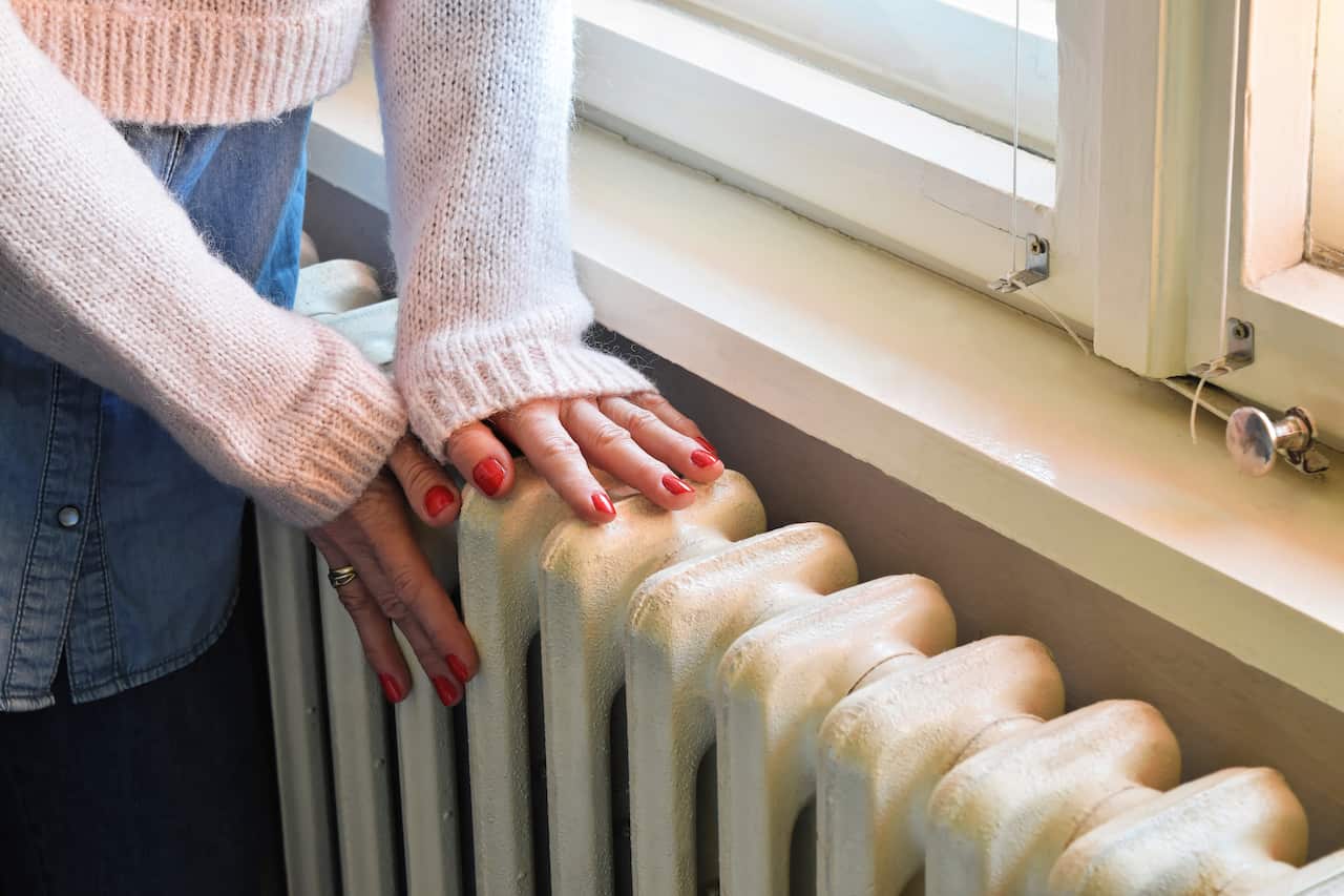 A woman touching a heater in her home.