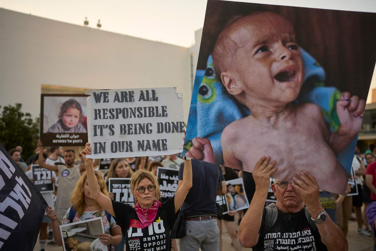 Protesters march with image of starving child and signs reading: "WE ARE ALL RESPONSIBLE IT'S BEING DONE IN OUR NAME."