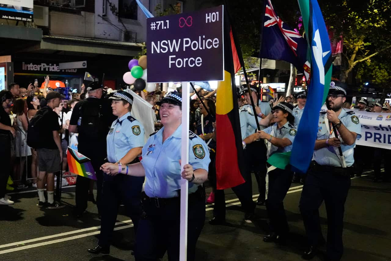A person in a police uniform holds a sign that says NSW police force
