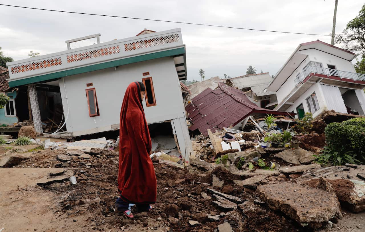 A school student dressed in red walks passes their collapsed Islamic boarding school caused by a 5.6 magnitude earthquake, in Cianjur, Indonesia.
