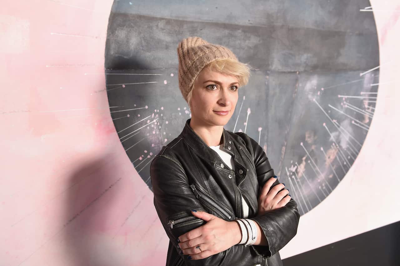 A woman standing in front of a pink and black wall.