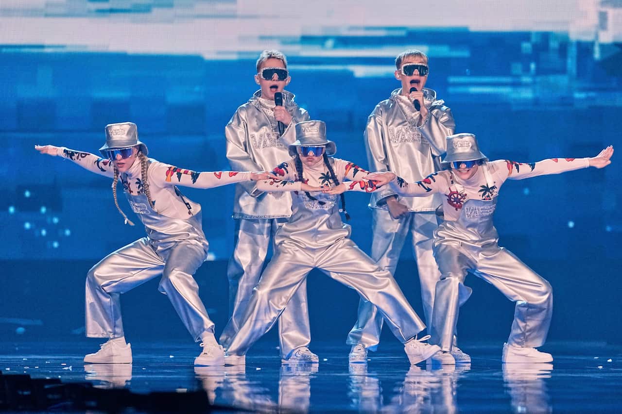 Performers on stage wearing silver tracksuits