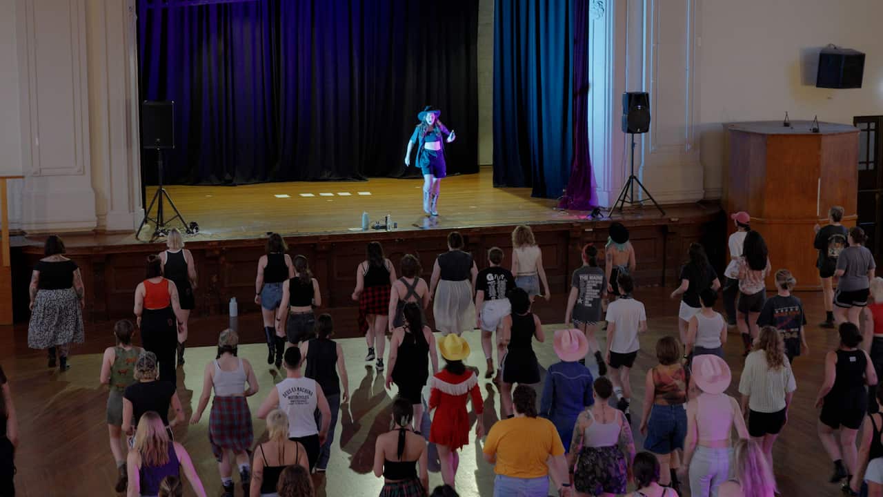 A crowd of people dancing looking at another person on stage dancing