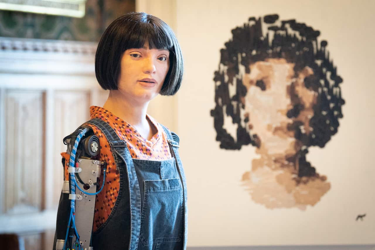 Robot Ai-Da in front of a self-portrait