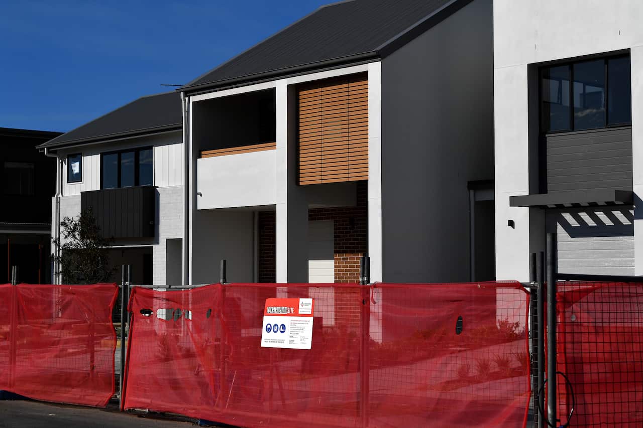 A new townhouse under construction surrounded by a temporary fence.
