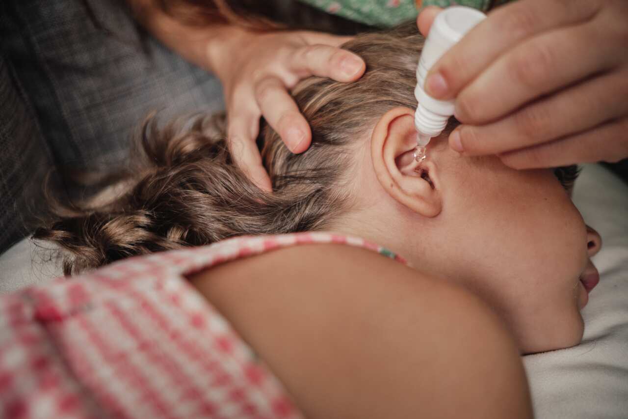 Mother putting drops in little girl's ear