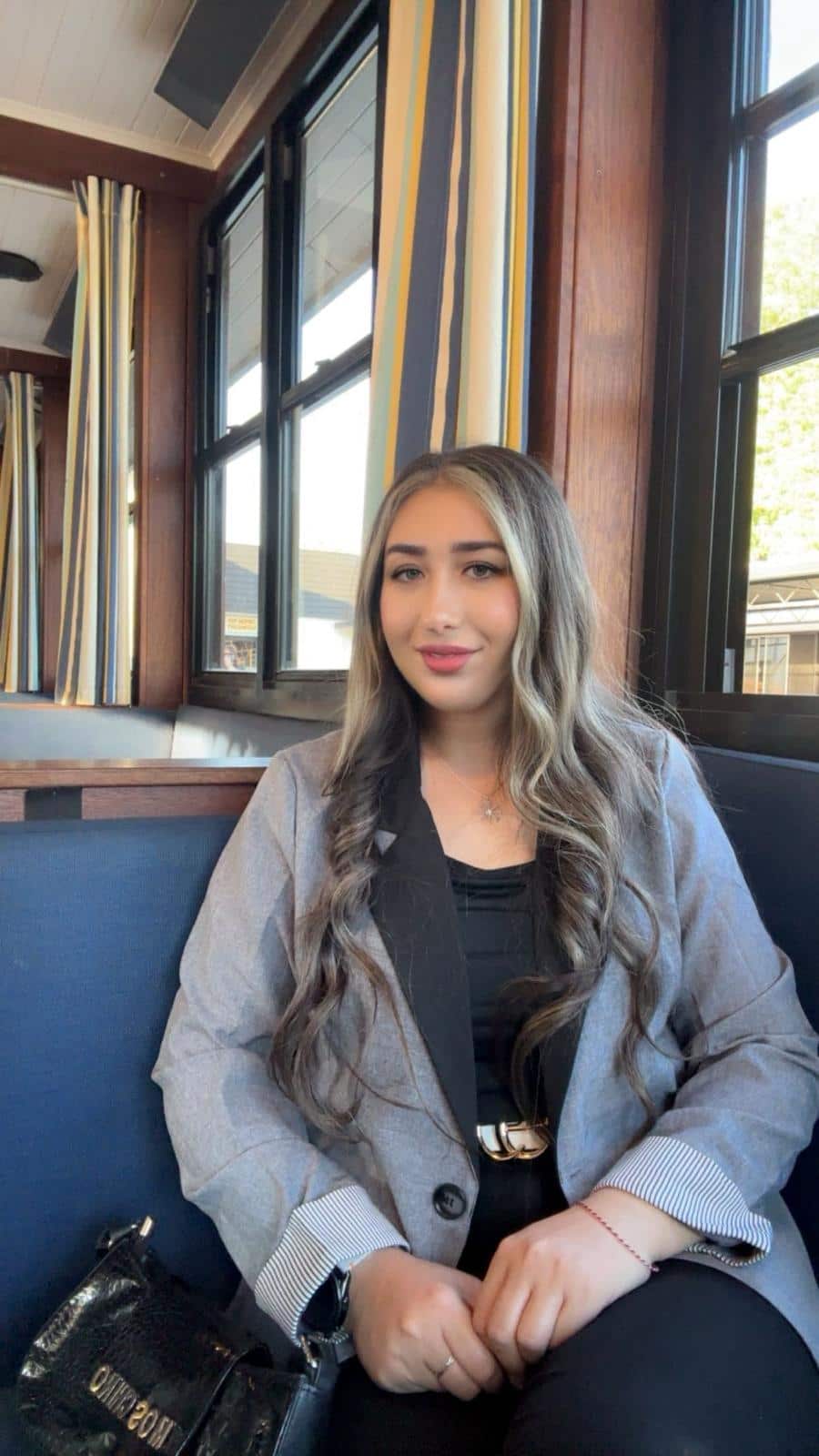A young woman sitting down in a grey blazer.