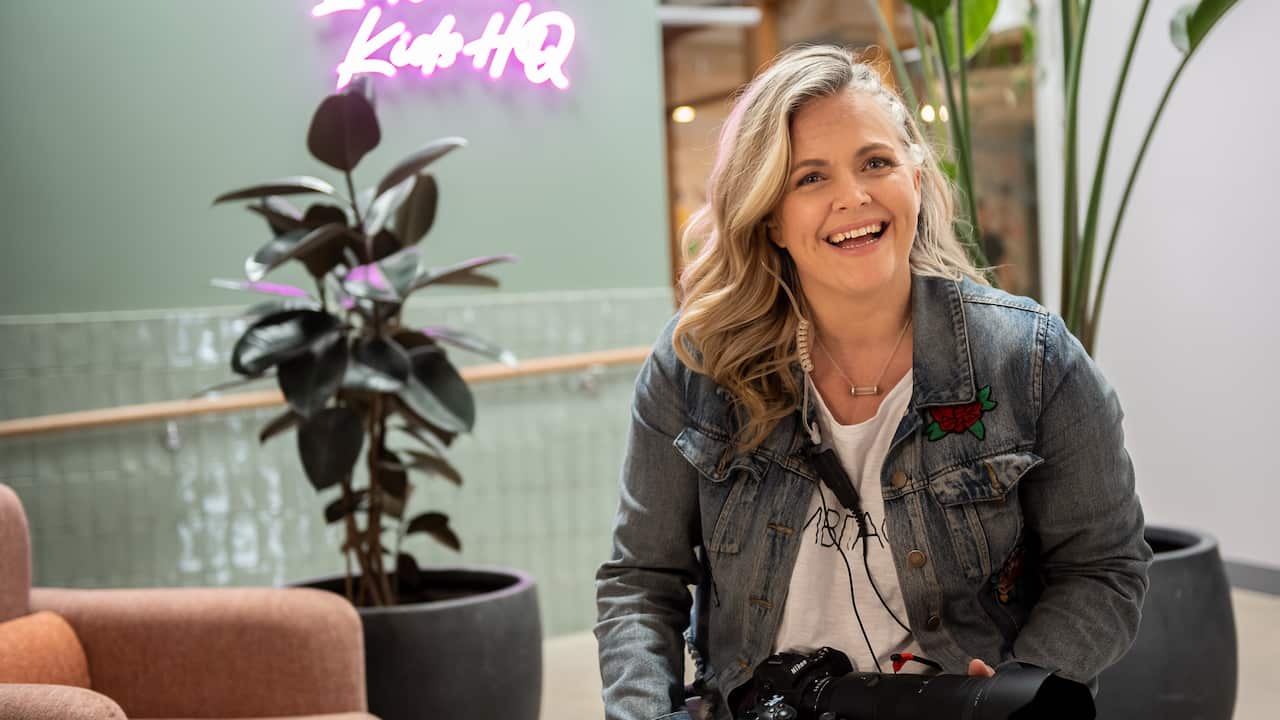 Taryn Brumfitt sitting in an office holding a camera
