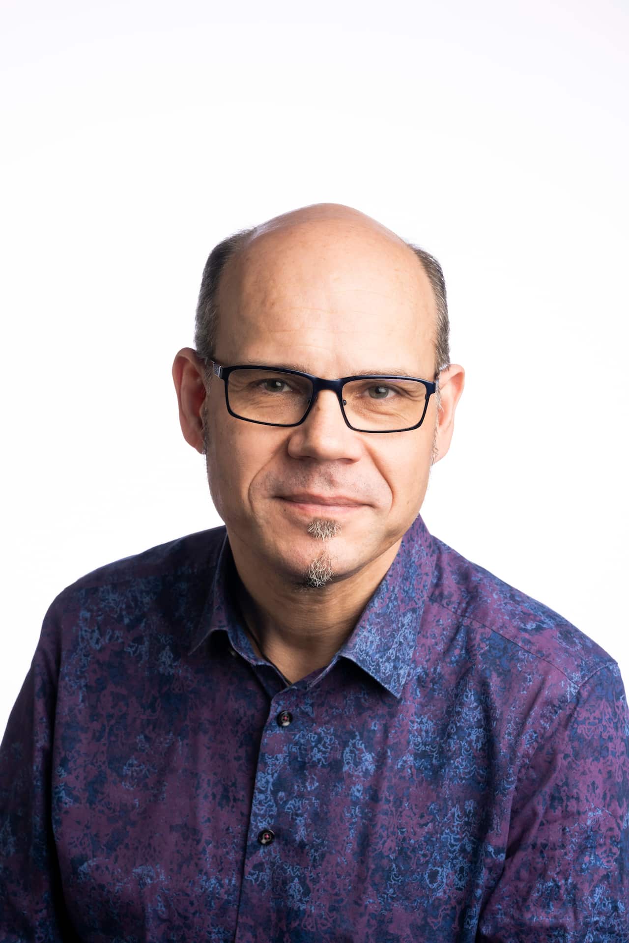 A man in a collared shirt wearing glasses.