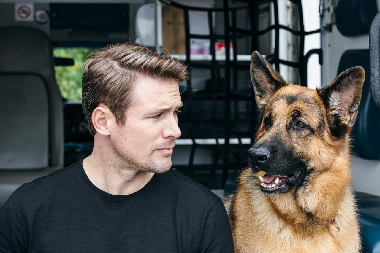 A man sits beside a German Shepherd dog.jpeg
