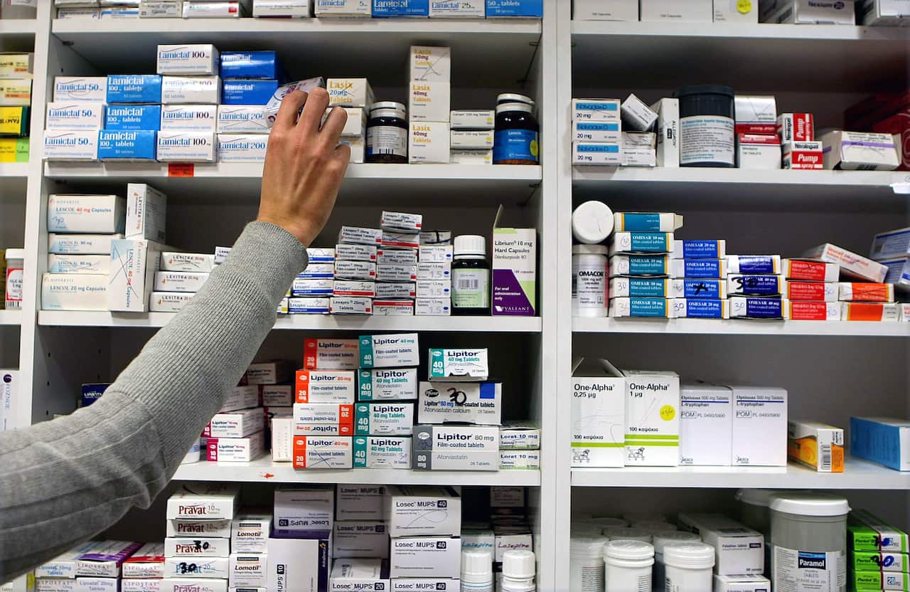 A person grabbing medication from a shelf in the pharmacy