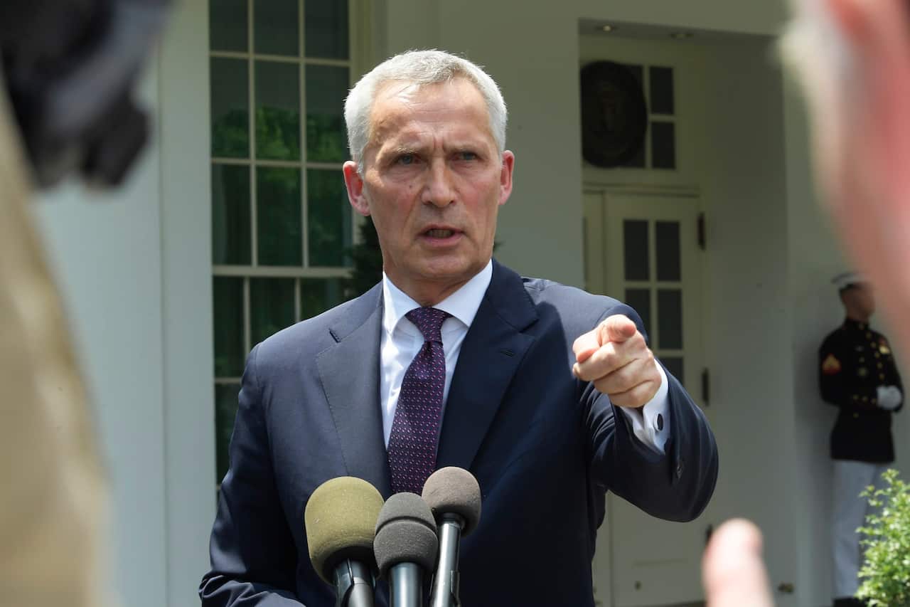 A man in a suit speaking into microphones during a press conference.