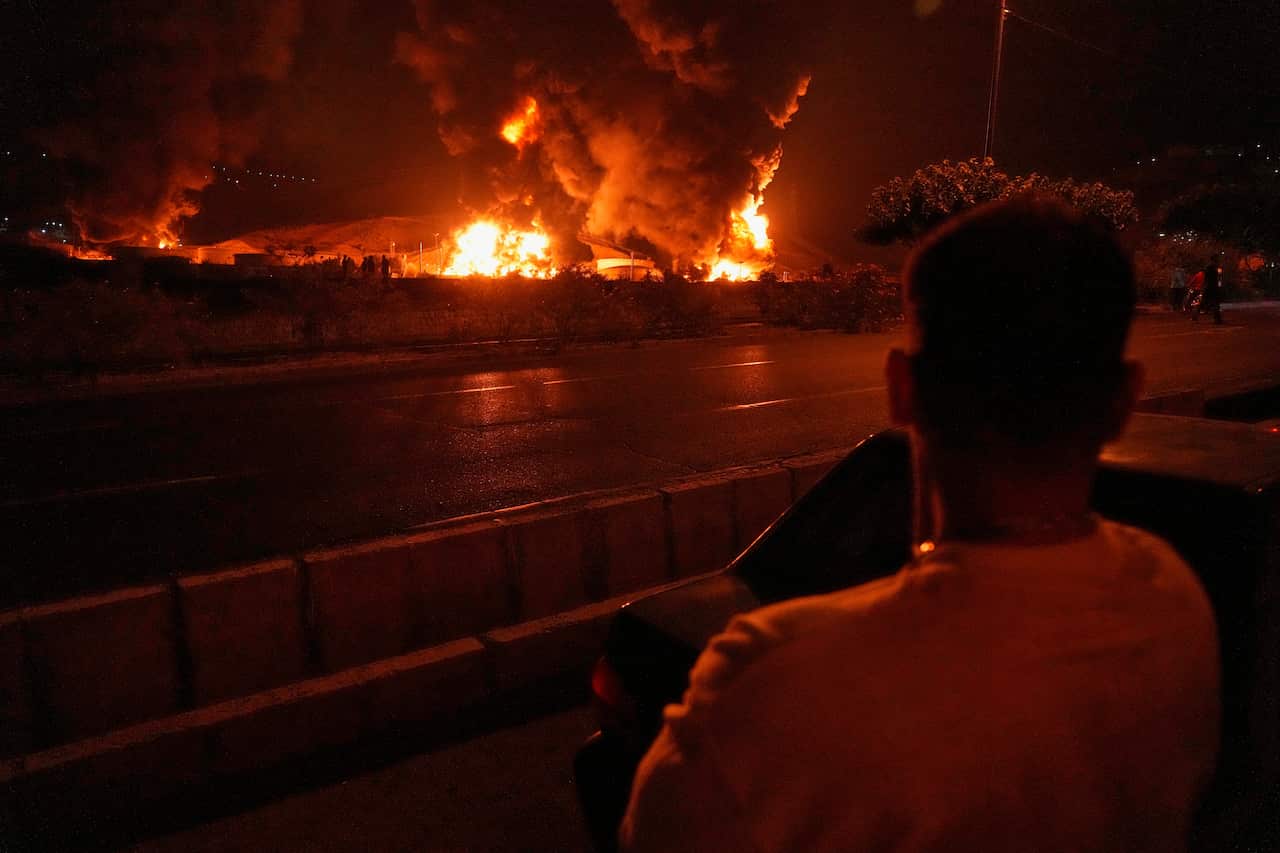 A man looks at blazes of an oil storage location in Iran