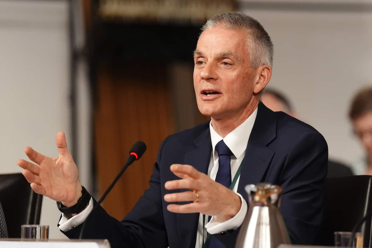 Man in suit sits in front of microphone