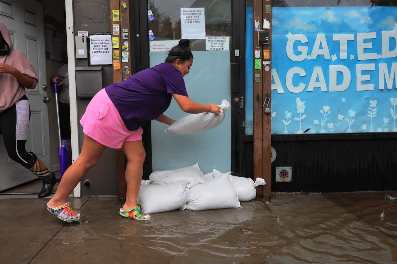 A woman placing sandbags out the front of a building.