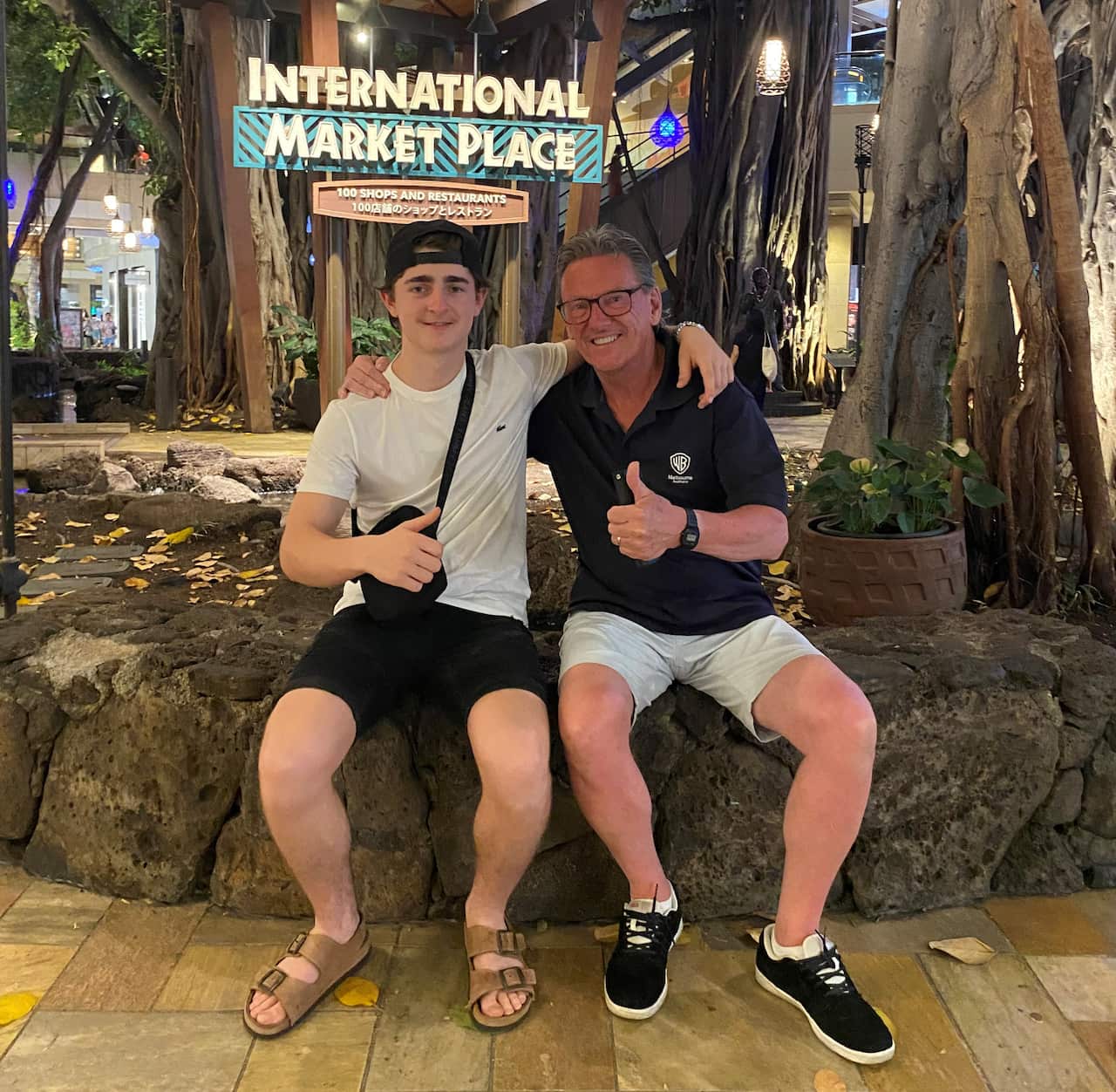A teenage boy and a middle aged man smiling at a camera with thumbs up