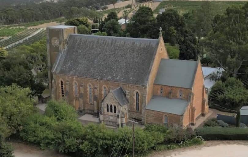 An historic churchin a rural area surrounded by grape vines.