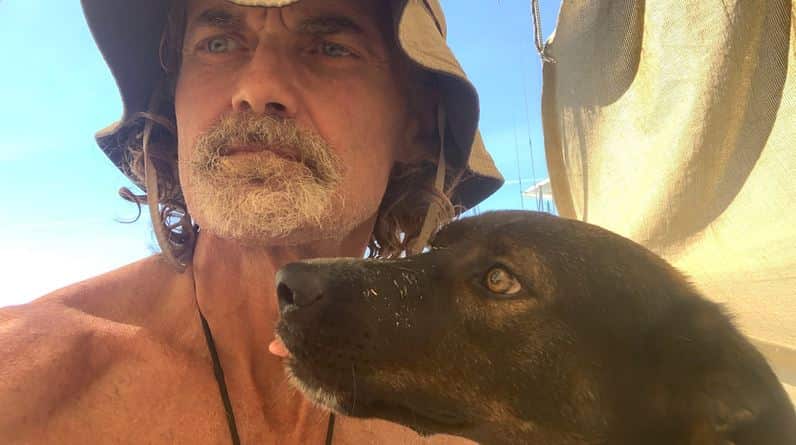 A man and his dog poking its tongue out.