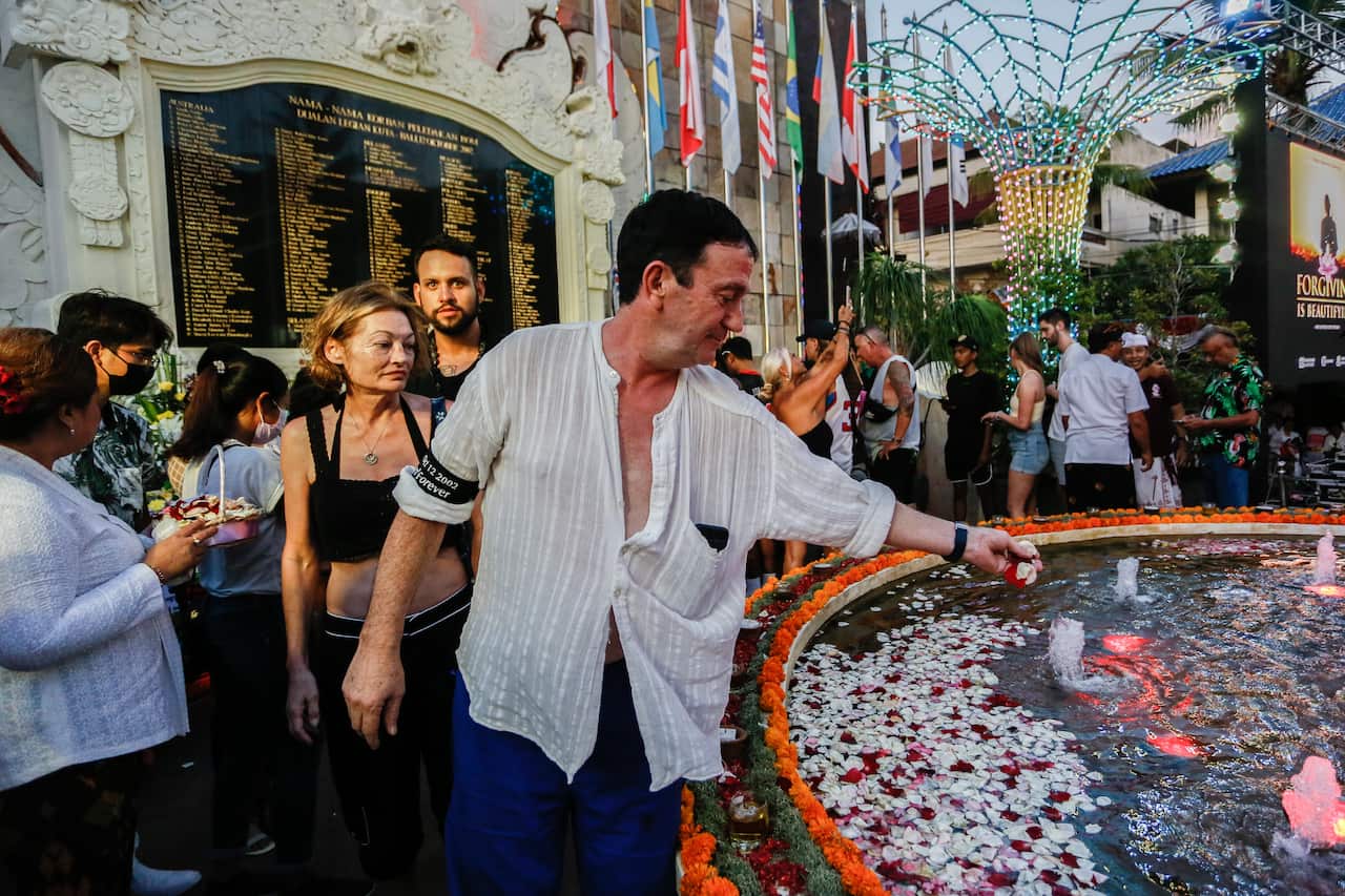 Man putting flowers on remembrance pond in Bali.