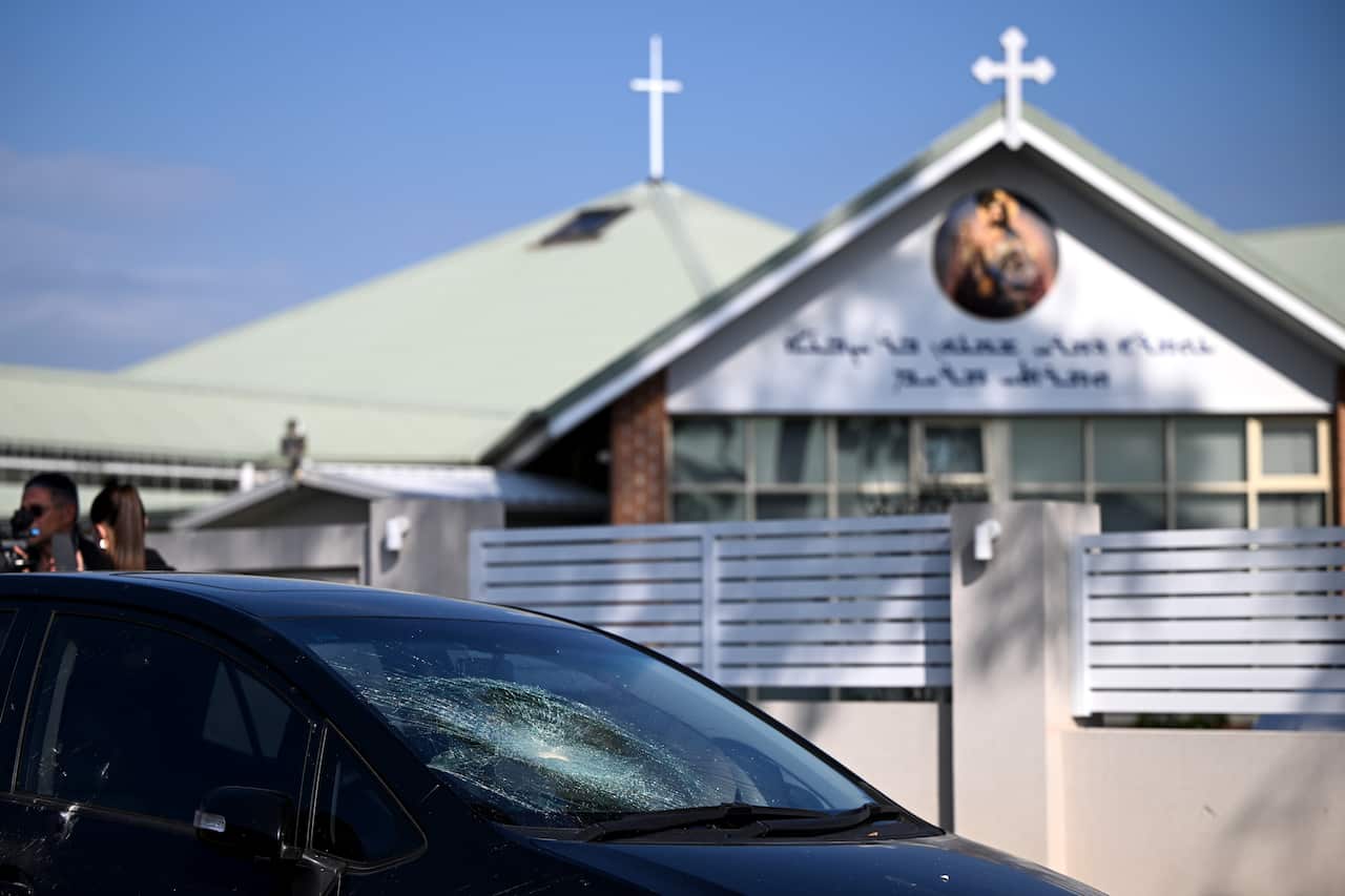 The shattered windscreen of a car in the foreground of a church.