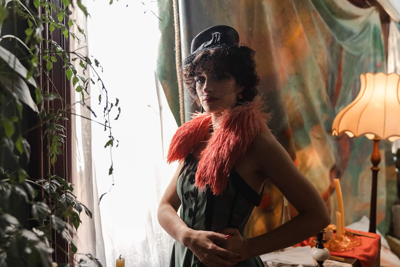 A woman in a cabaret style outfit looks into the camera