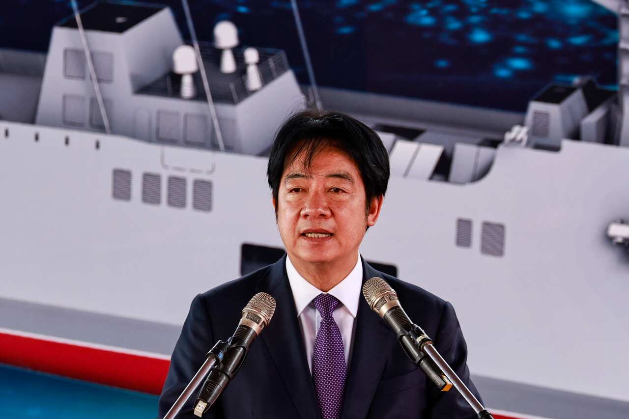 An Asian man speaks into two microphones