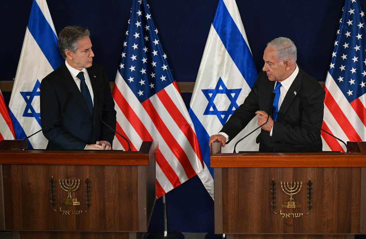 Benjamin Netanyahu and Antony Blinken, both wearing suits, stand in front of lecterns and Israeli and US flags.
