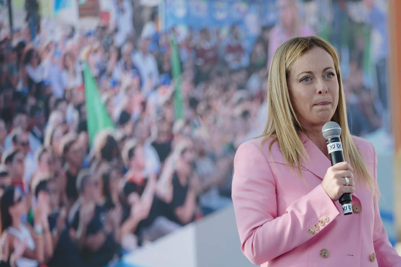 Woman in pink blazer speaks on mic