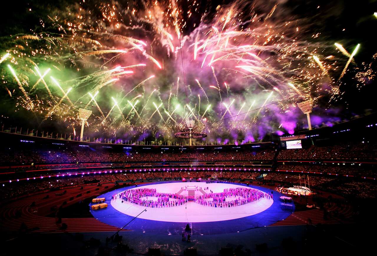 Brightly-coloured fireworks light up the sky in a large sports stadium.