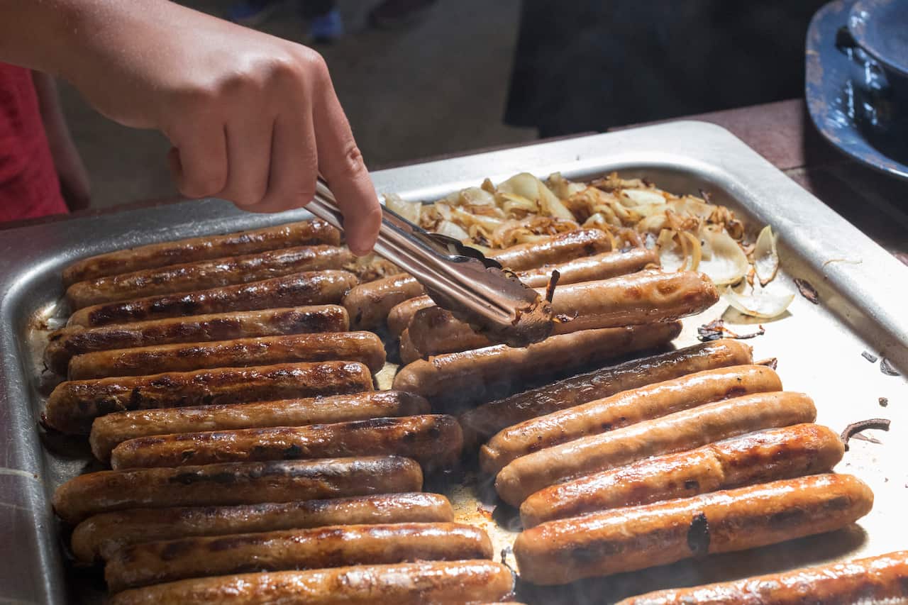 Teenage male cooking sausages for a Barbecue.