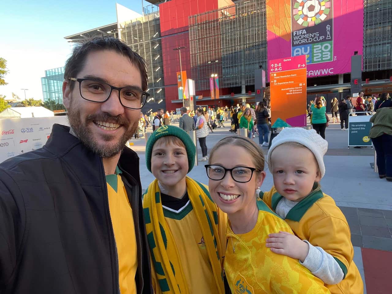 A family wearing Matildas jerseys outside a stadium.