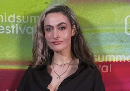 A woman with long hair smiles at the camera with a neutral expression on her face.
