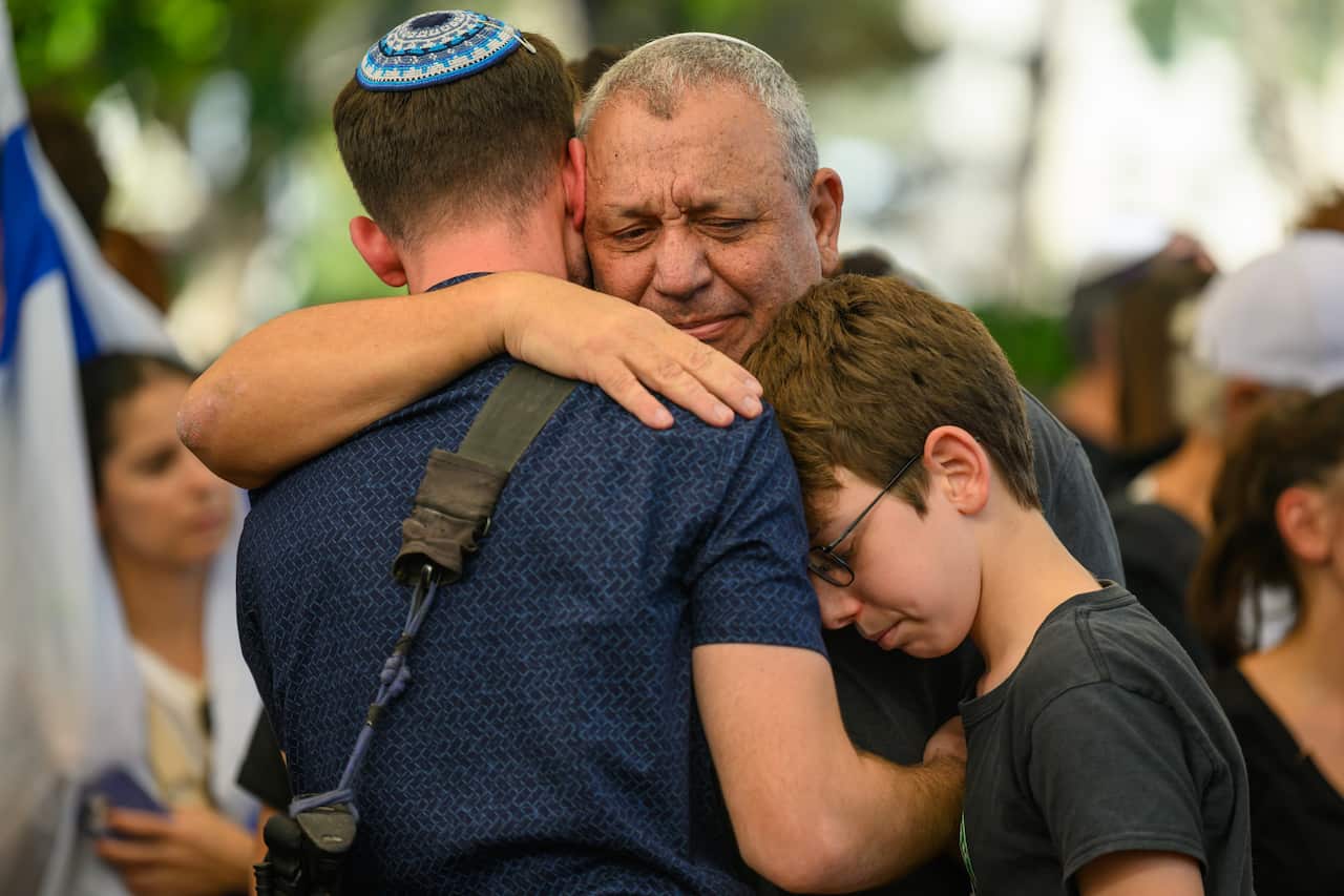A man emotionally embracing a younger man and a child.