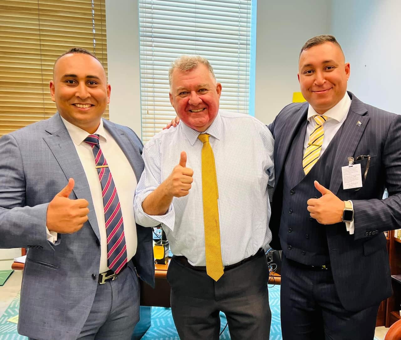 Three men stand and smile.