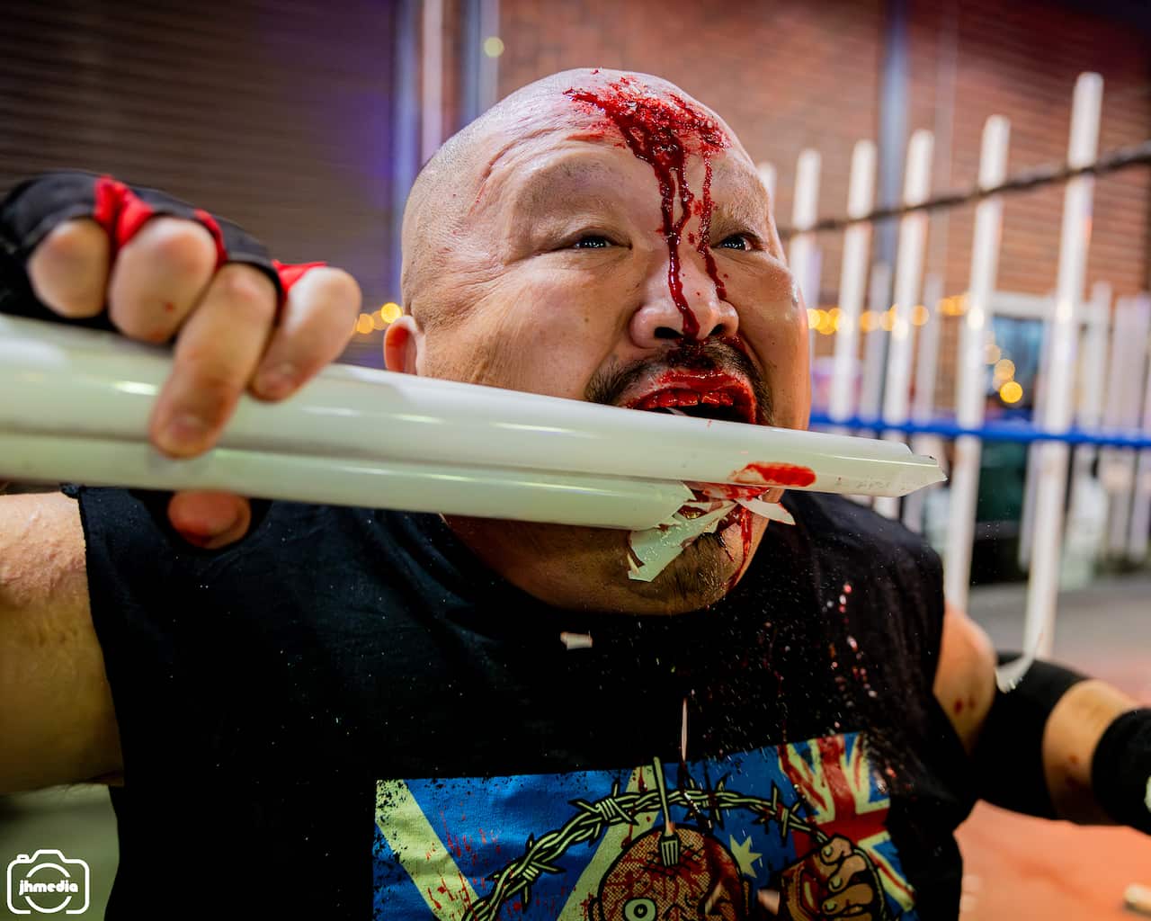 A man eating a glass tube with blood coming out of his forehead.