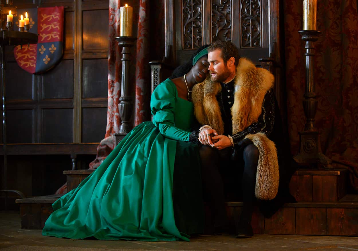 Actor Jodie Turner-Smith in an emerald gown seated and leaning on the shoulder of fellow actor Mark Stanley in a fur-lined coat, as Anne Boleyn and Henry VIII in miniseries Anne Boleyn.jpg