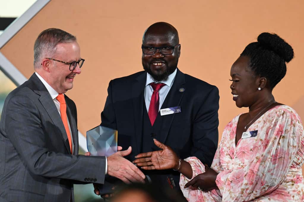 A man presents an award to a woman, alongside a second man. 