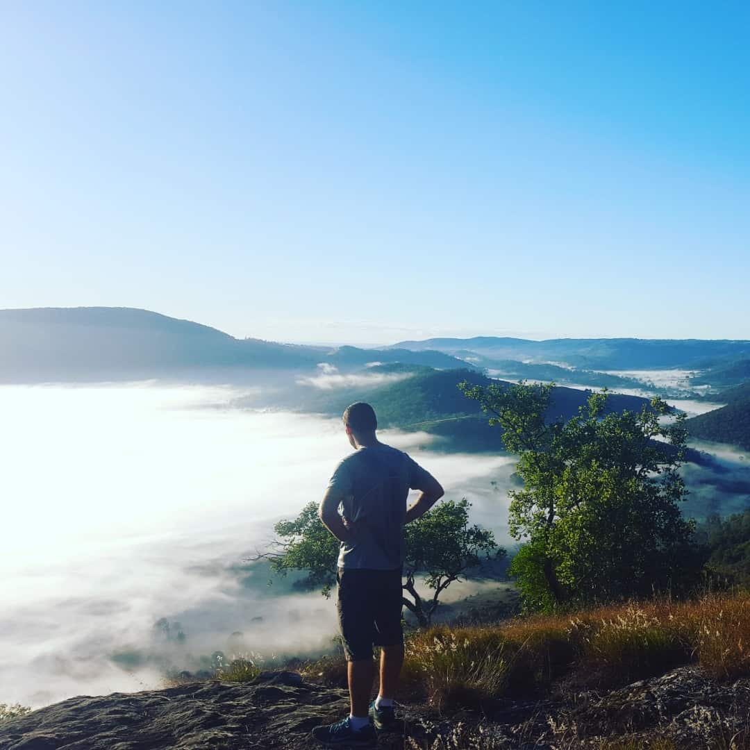 Austin standing on a mountain, looking at the view above the clouds. The image was taken on the morning he died. 