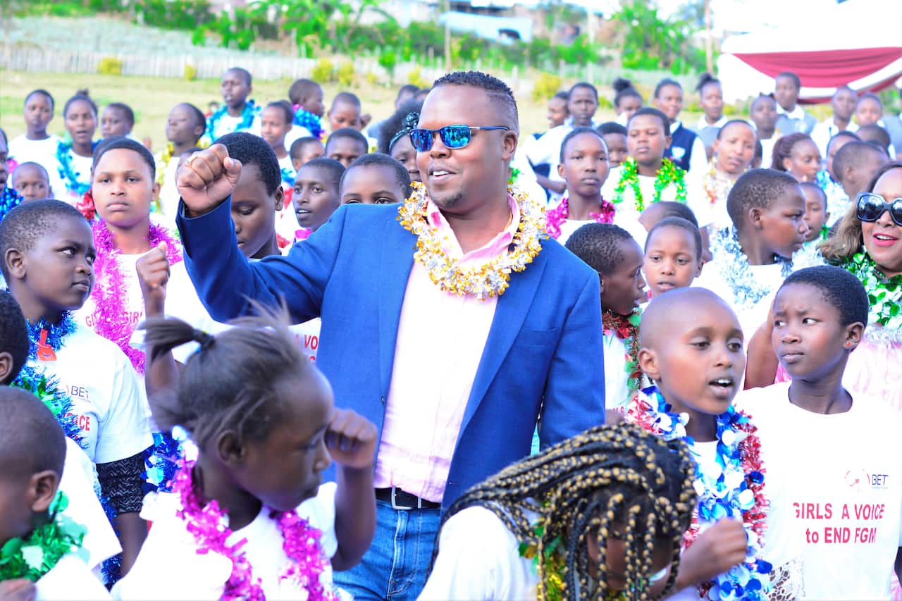 Bernard Korir standing outside and surrounded by people. He is holding up his right fist.